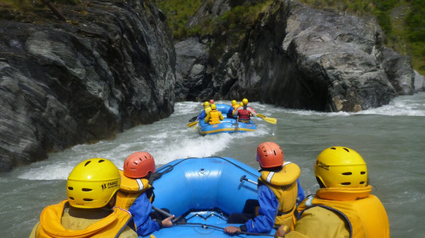 Group of tourists rafting through the Shotover River's canyons.