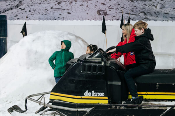 Children riding the an all-terrain vehicle over the ice.
